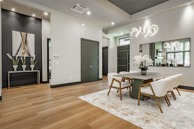 dining area with plenty of natural light, a high ceiling, a chandelier, and light hardwood / wood-style floors