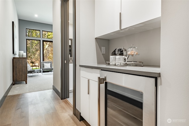 bar with white cabinetry, light colored carpet, and wine cooler