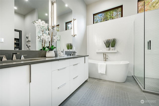 bathroom featuring double vanity, plus walk in shower, and tile patterned flooring