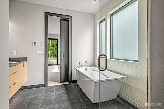 bathroom with a freestanding tub, tile patterned flooring, and vanity