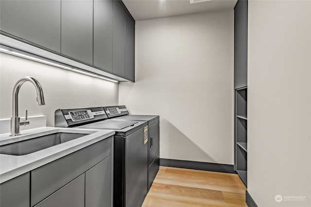 laundry room with light hardwood / wood-style floors, washer and clothes dryer, sink, and cabinets