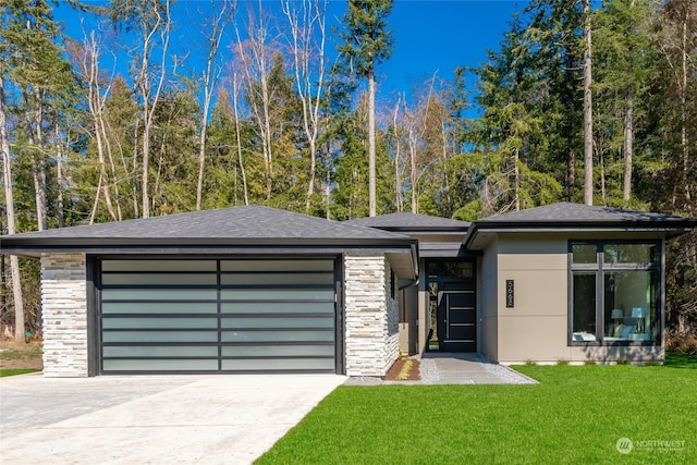 prairie-style house featuring an attached garage, stone siding, driveway, a front lawn, and a shingled roof