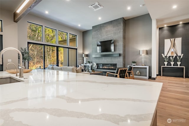 living area with visible vents, a fireplace, wood finished floors, recessed lighting, and a high ceiling
