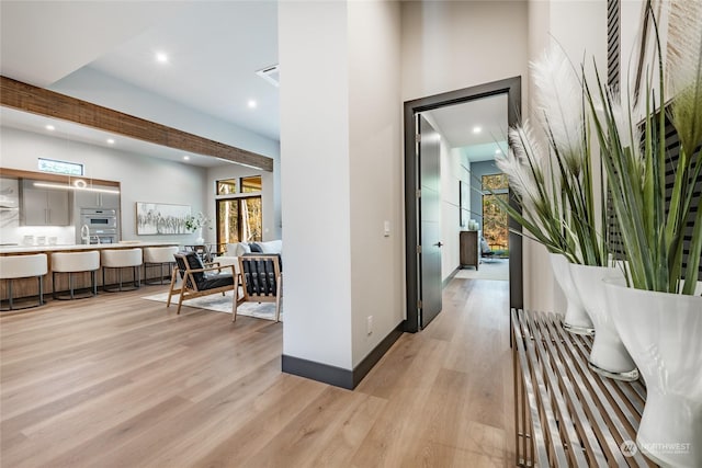 hallway featuring baseboards, light wood-type flooring, and recessed lighting