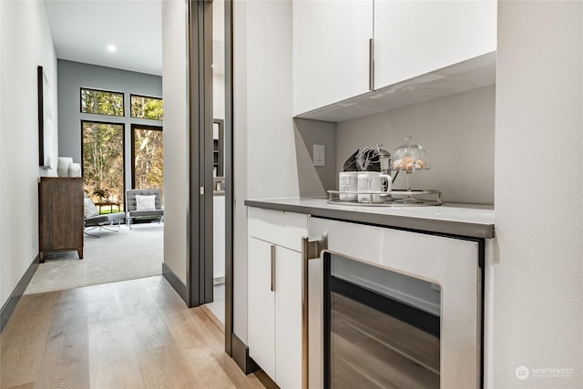 bar with baseboards, light wood-style flooring, and wine cooler