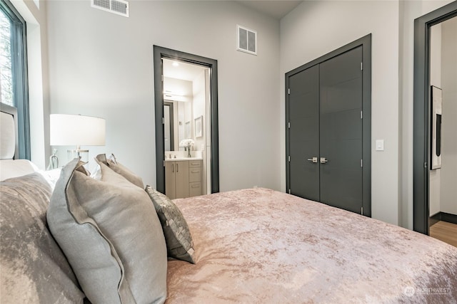 bedroom featuring ensuite bath, a closet, and visible vents