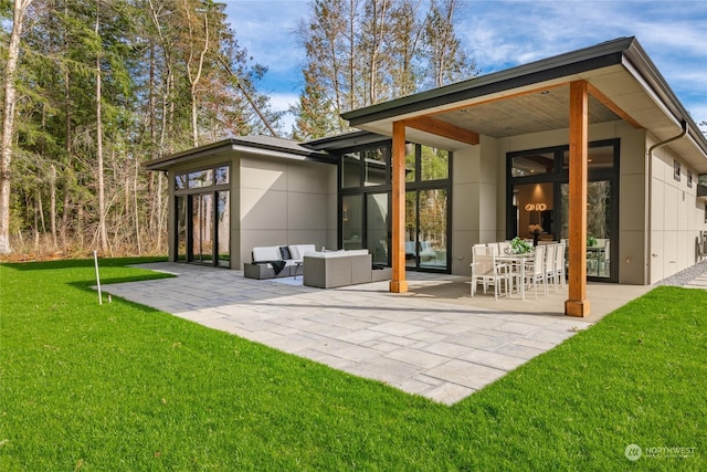 rear view of house featuring outdoor lounge area, stucco siding, a yard, and a patio area