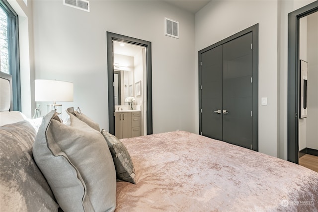 bedroom with a closet, hardwood / wood-style floors, and ensuite bath