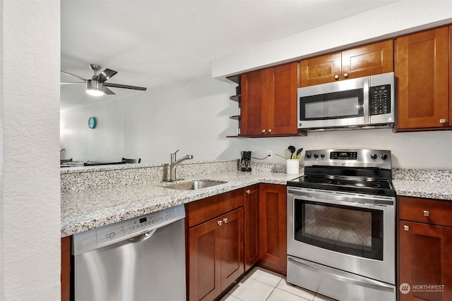 kitchen with light tile patterned flooring, sink, ceiling fan, stainless steel appliances, and light stone countertops