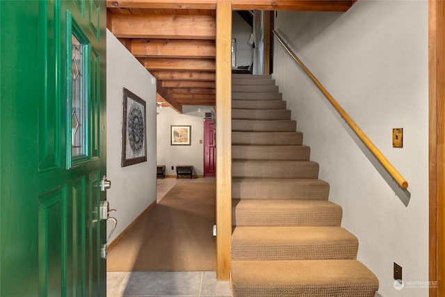 stairway featuring wooden ceiling, tile patterned floors, and beamed ceiling