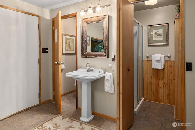 bathroom with sink, an enclosed shower, and wooden walls