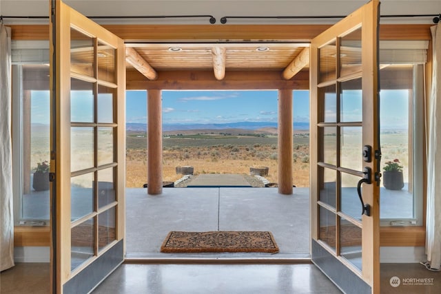 doorway with concrete flooring, a mountain view, wood ceiling, and french doors