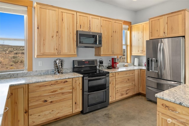 kitchen featuring light stone counters, light brown cabinetry, and stainless steel appliances