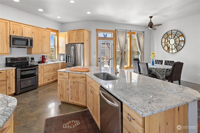 kitchen featuring light stone counters, appliances with stainless steel finishes, sink, and a kitchen island with sink