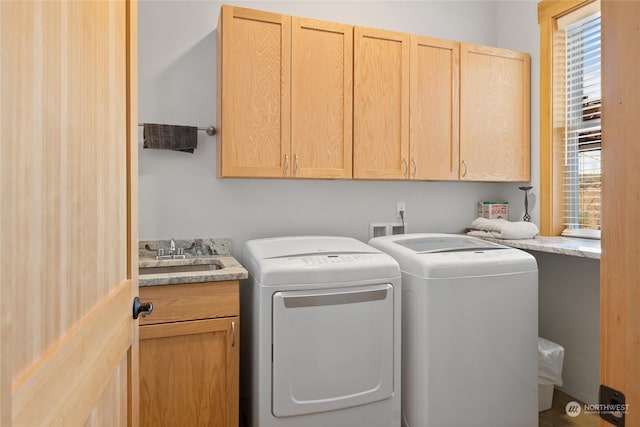 clothes washing area featuring cabinets, washing machine and dryer, sink, and a healthy amount of sunlight