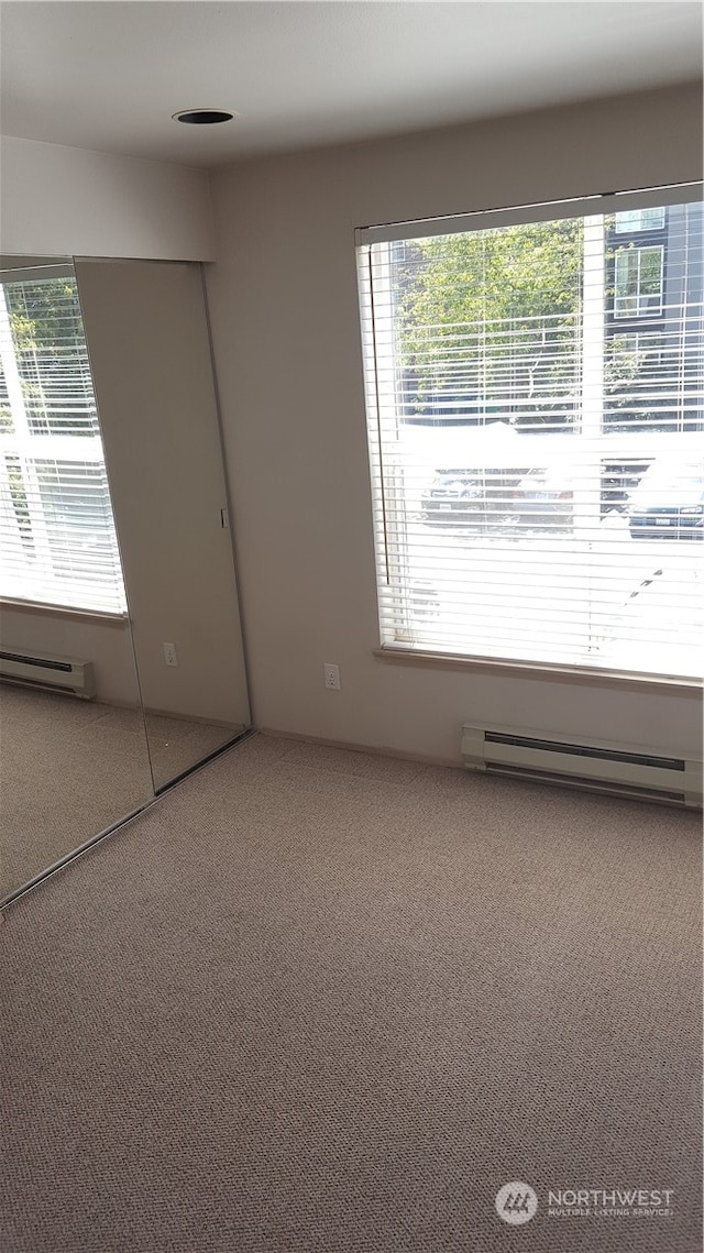 unfurnished room with carpet floors, a baseboard radiator, and a healthy amount of sunlight