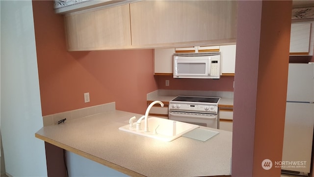 kitchen featuring sink, light brown cabinets, and white appliances