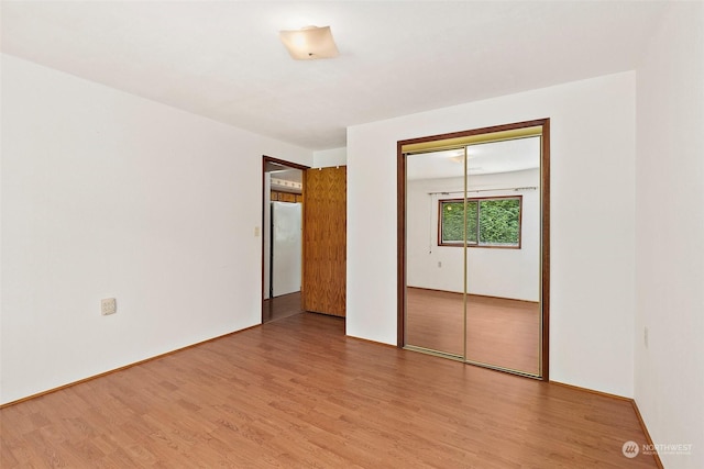 unfurnished bedroom featuring white fridge, hardwood / wood-style floors, and a closet