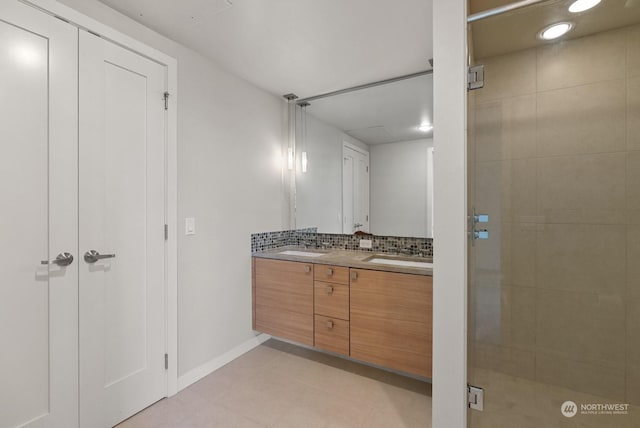 bathroom with tasteful backsplash, vanity, tile patterned flooring, and a shower with door