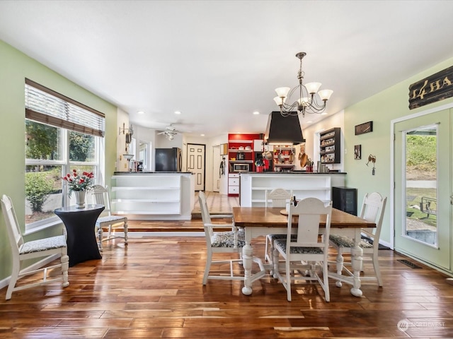 dining room featuring hardwood / wood-style flooring, ceiling fan with notable chandelier, and plenty of natural light