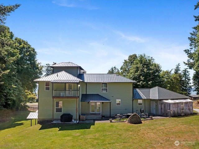 rear view of property featuring a balcony and a lawn