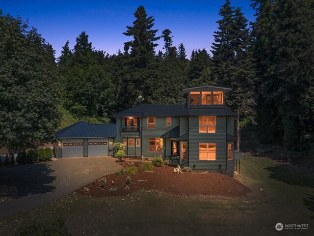 colonial-style house featuring a garage, a balcony, metal roof, and concrete driveway