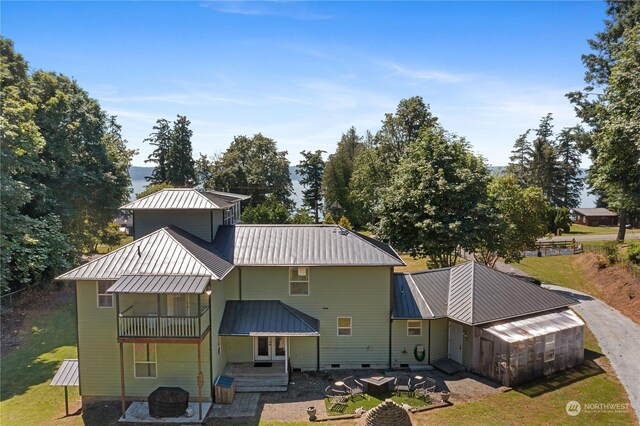 back of house with an outdoor fire pit, a patio area, a balcony, a yard, and metal roof