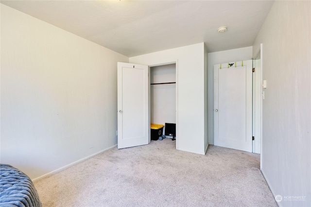 unfurnished bedroom featuring light carpet and a closet