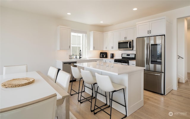 kitchen with appliances with stainless steel finishes, a center island, a breakfast bar area, and white cabinets