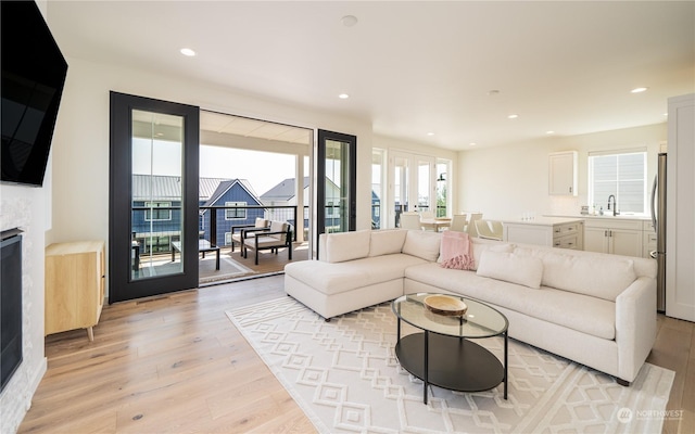 living room featuring french doors, sink, and light hardwood / wood-style floors