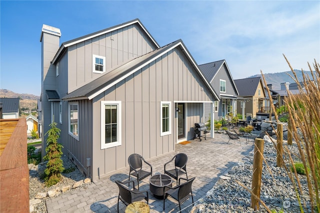 rear view of house with a mountain view, a patio, and an outdoor fire pit