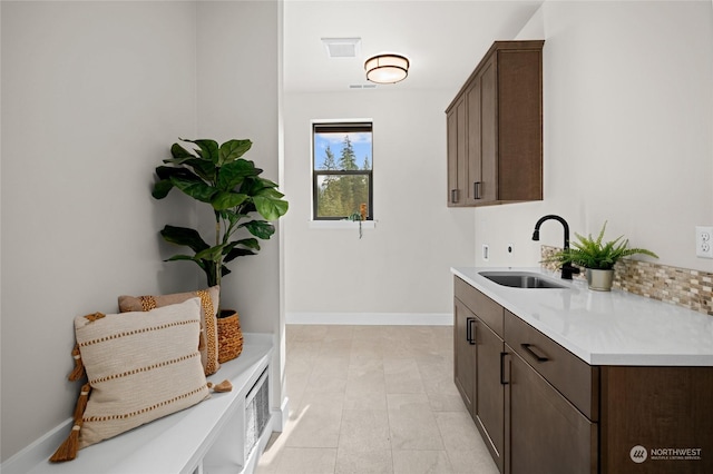 clothes washing area with visible vents, baseboards, cabinet space, and a sink