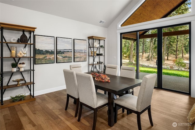 dining room with visible vents, vaulted ceiling, wood finished floors, and baseboards