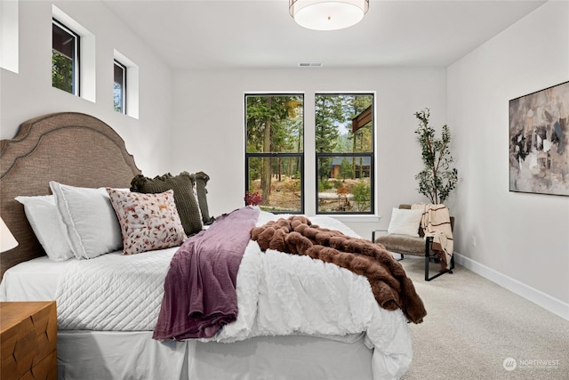 carpeted bedroom featuring visible vents, baseboards, and multiple windows