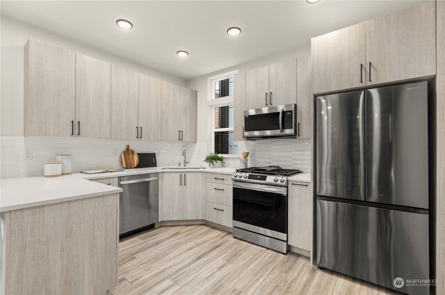 kitchen featuring light hardwood / wood-style flooring, light brown cabinetry, appliances with stainless steel finishes, sink, and decorative backsplash