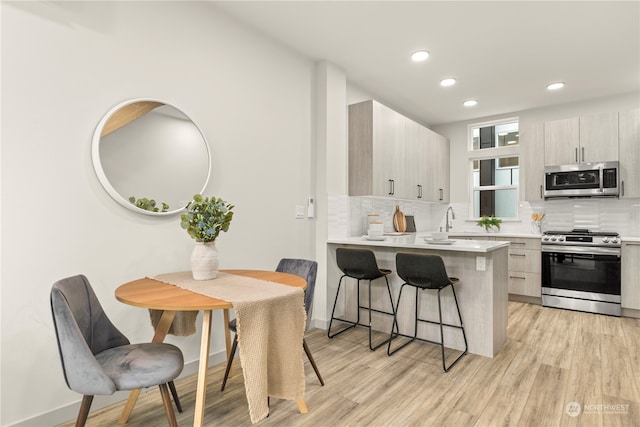 kitchen featuring a breakfast bar area, kitchen peninsula, appliances with stainless steel finishes, and tasteful backsplash