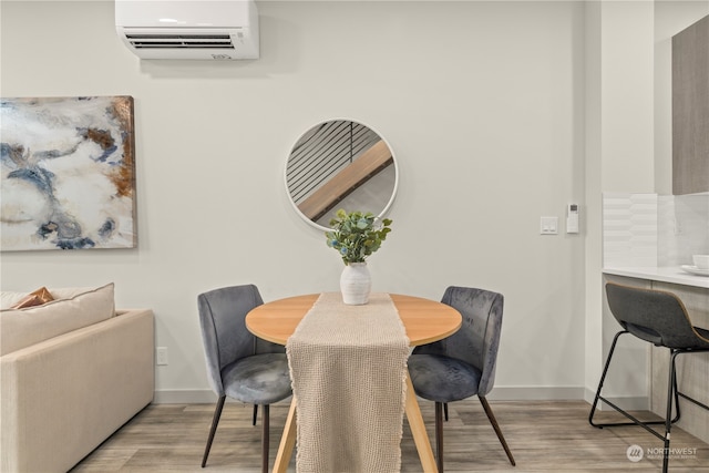 dining room with light hardwood / wood-style floors and a wall unit AC