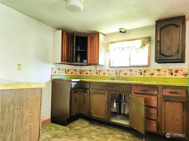 kitchen featuring light countertops, a sink, a textured ceiling, and light floors