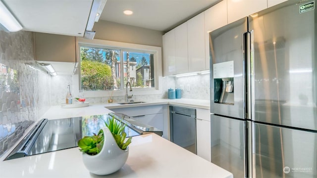 kitchen with stainless steel refrigerator with ice dispenser, decorative backsplash, white cabinets, and sink