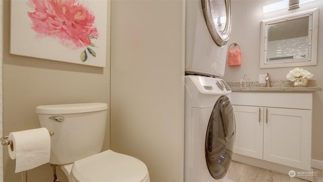 bathroom with toilet, vanity, and stacked washer and dryer