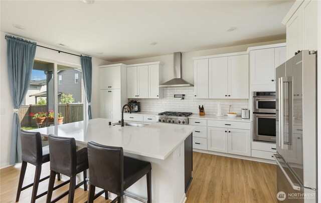 4429 Hibiscus Cir SW, Port Orchard, WA 98367 - kitchen with wall chimney range hood, stainless steel appliances, a sink, light wood-style flooring, and backsplash
