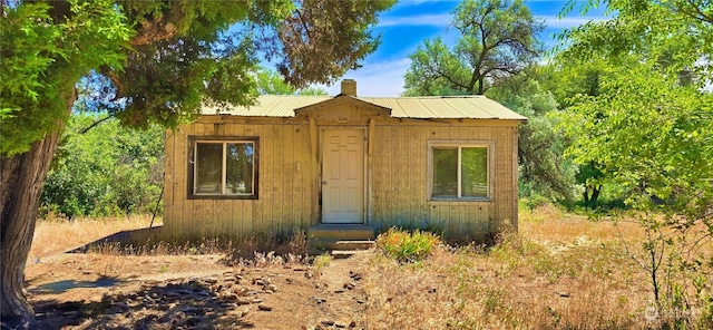 view of front of property featuring metal roof and a chimney