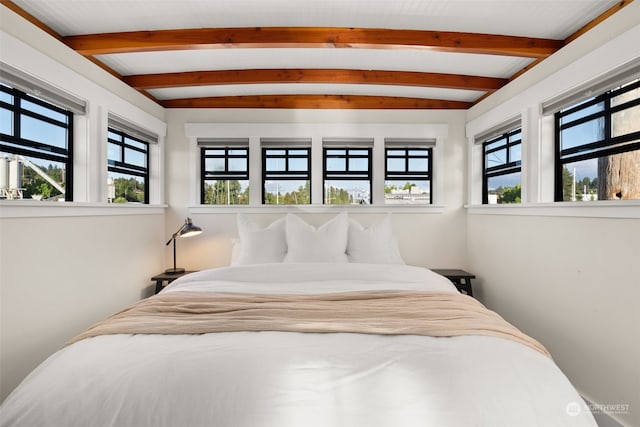 bedroom with lofted ceiling with beams and multiple windows