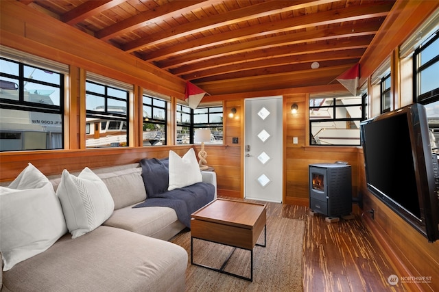 living room featuring beam ceiling, a wood stove, wooden walls, and wooden ceiling