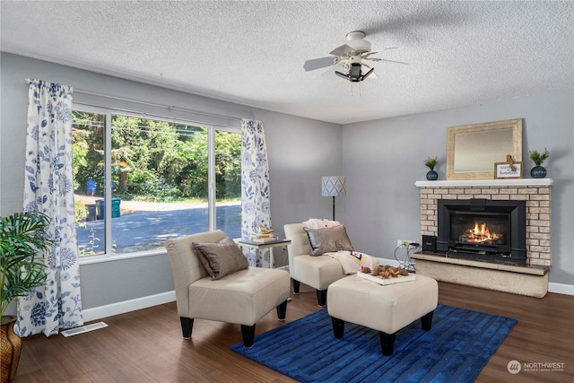 living area with a brick fireplace, baseboards, visible vents, and wood finished floors