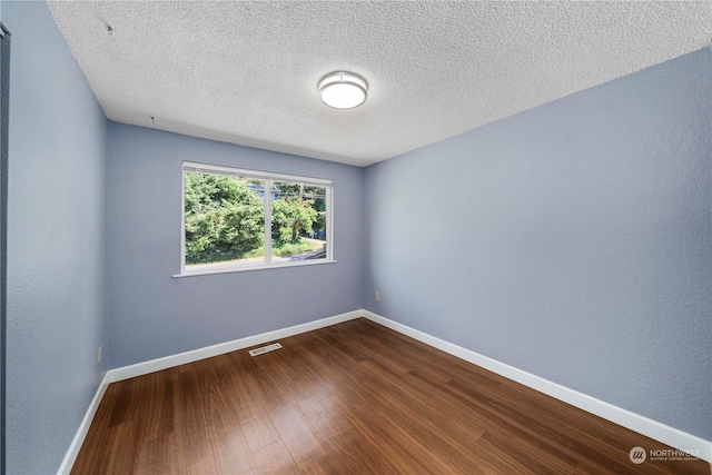 unfurnished room with hardwood / wood-style flooring and a textured ceiling