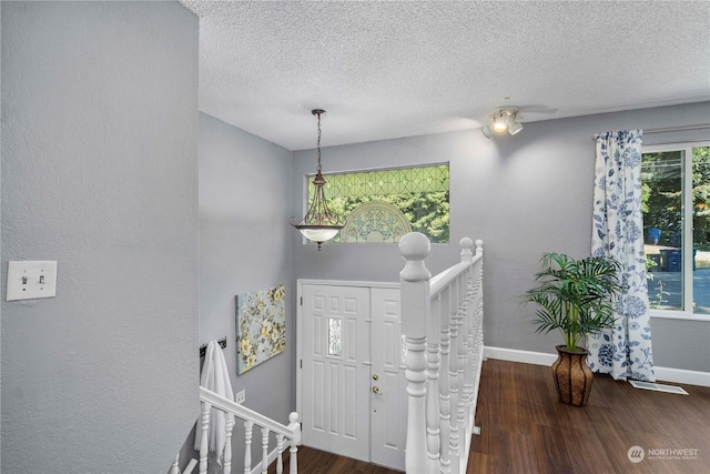 foyer with a textured ceiling, wood finished floors, and baseboards