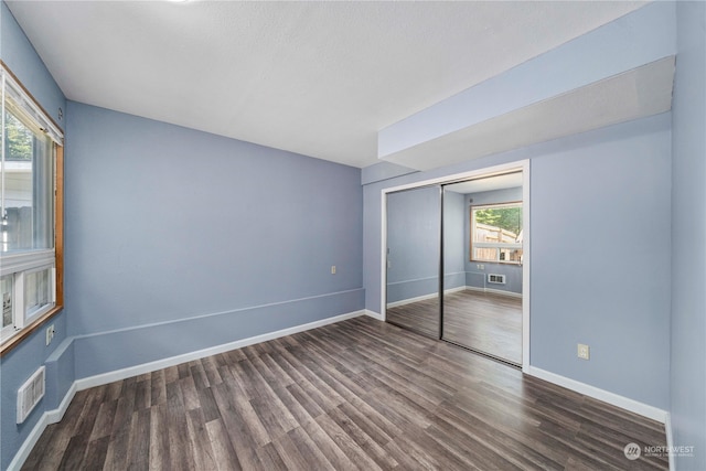 unfurnished bedroom with a closet and dark hardwood / wood-style flooring