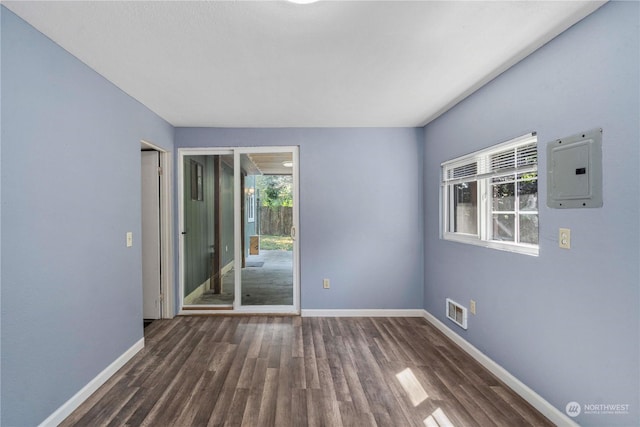 empty room with visible vents, wood finished floors, electric panel, and baseboards