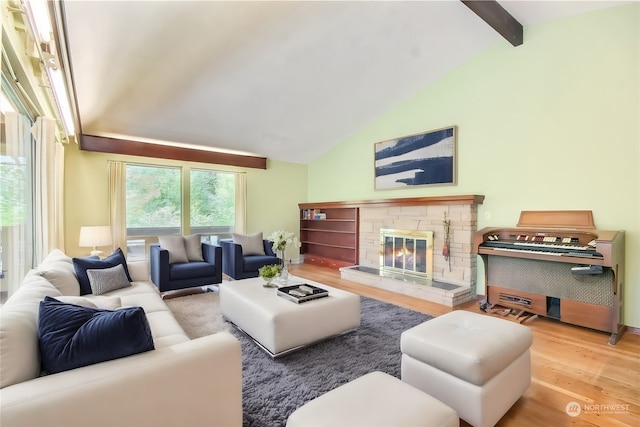 living room with wood-type flooring, lofted ceiling with beams, and a stone fireplace